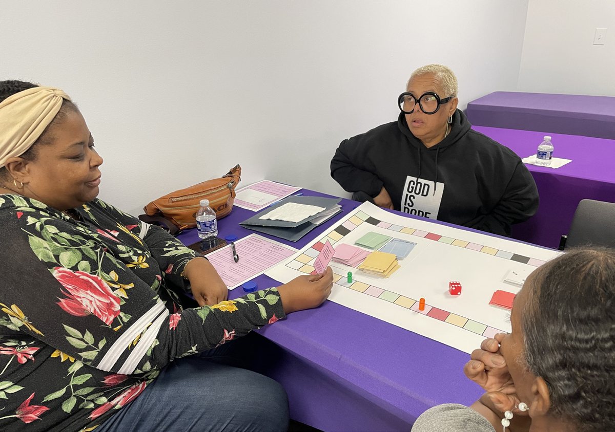 A grandmother in large glasses laughing while holding a game card