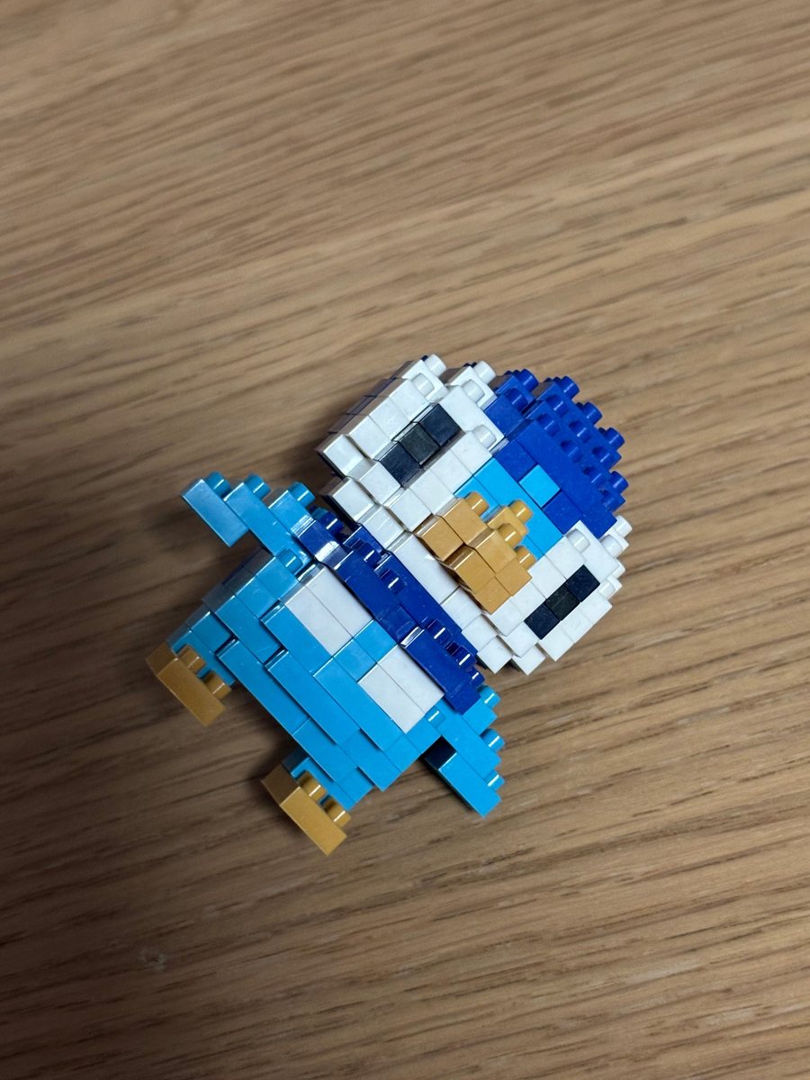 A small LEGO build of a blue and white bird on a wooden table